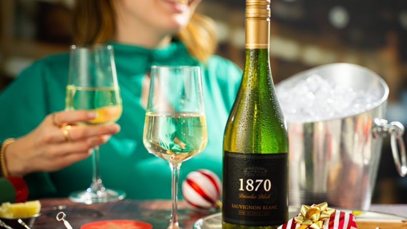 Errazuriz 1870 Sauvignon Blanc takes pride of place on a christmas table with a filled ice bucket behind it and someone drinking a glass of wine all together now with their friend